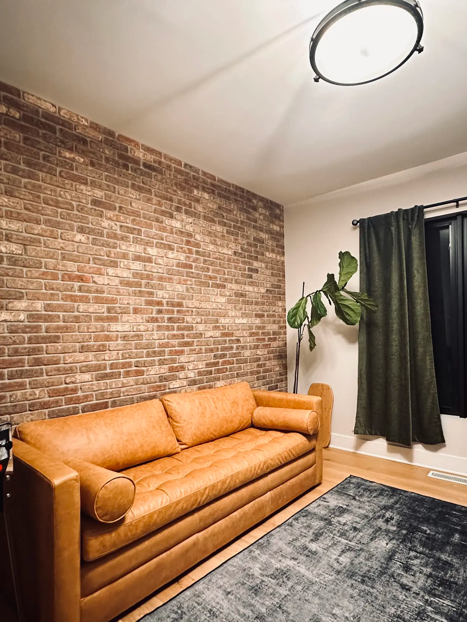 Couch on brick wall with hardwood floors and rug