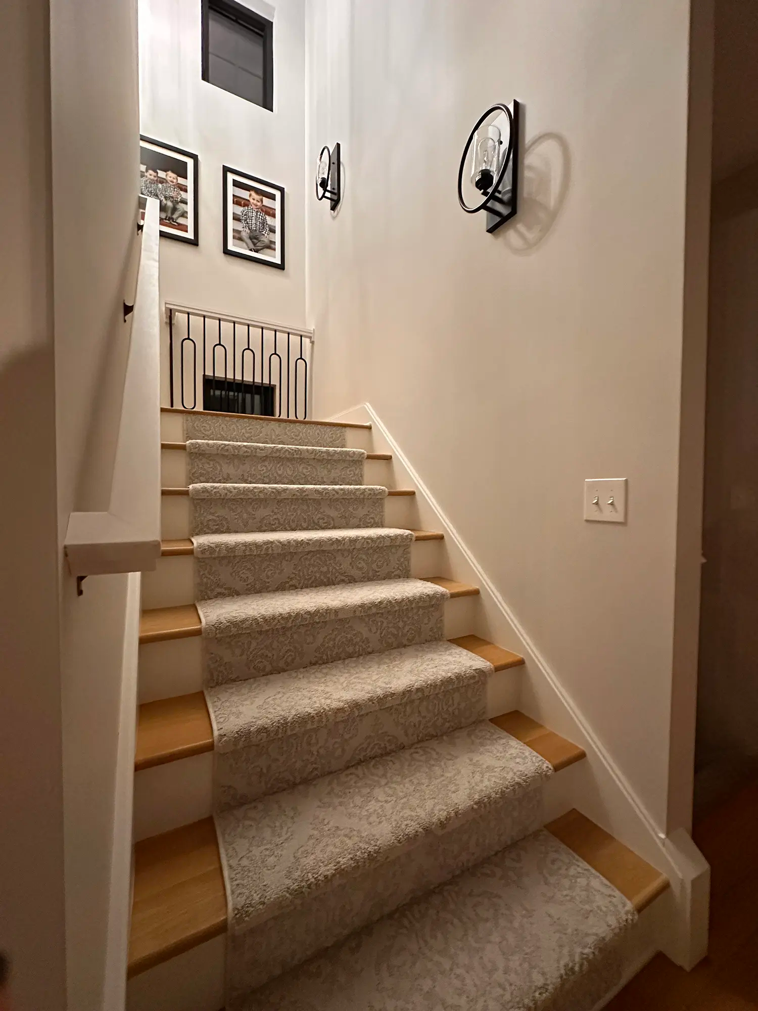 Carpeted stairs with railing and light fixture